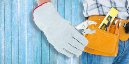 Technician using pliers over white background against wooden planks