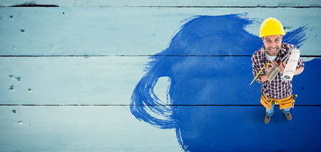 Frustrated handyman holding various tools against painted blue wooden planksの写真素材