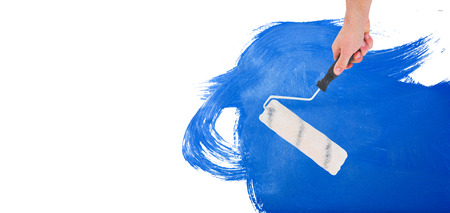 Handyman holding paint roller  against blue paintの写真素材