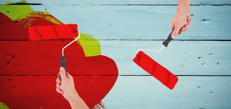 Handyman holding paint roller  against painted blue wooden planksの写真素材