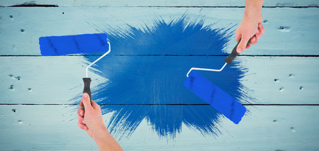 Handyman holding paint roller  against painted blue wooden planksの写真素材