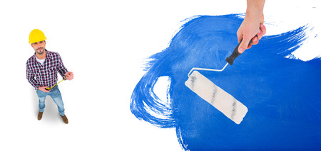 Handyman holding paint roller  against blue paintの写真素材