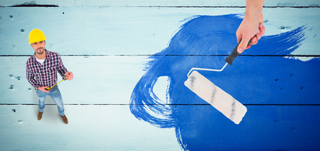 Handyman holding paint roller  against painted blue wooden planksの写真素材