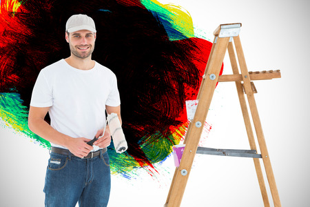 Man holding paint roller while standing by ladder against red green black yellow and blue paintの写真素材