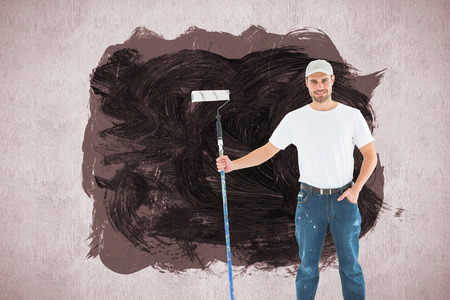 Confident man holding paint roller on white background against white and grey backgroundの写真素材