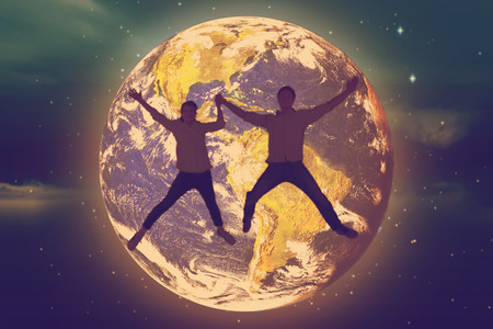 Couple jumping and holding hands against stars twinkling in night sky