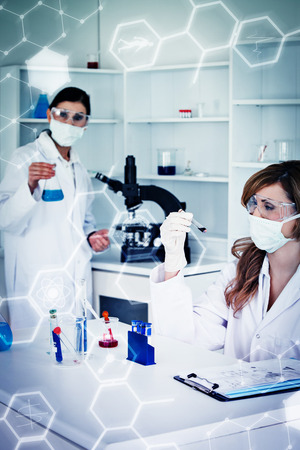 Science and medical graphic against scientists wearing masks and safety glassesの写真素材