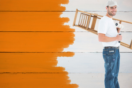 Man with paint roller and step ladder against painted blue wooden planksの写真素材