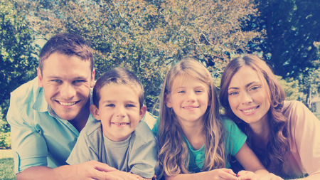 Happy family lying on the grass smiling at camera in park