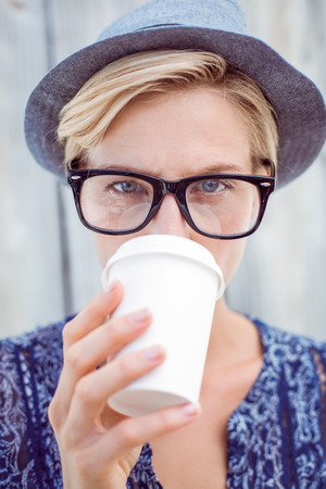Pretty blonde woman drinking coffee on wooden backgroundの写真素材