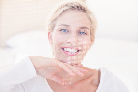 Smiling blonde woman looking at camera in the bedroomの写真素材