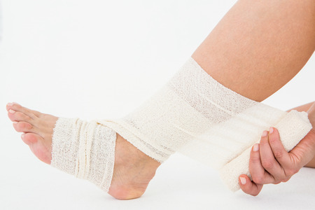 Sitting woman banding her ankle on white backgroundの写真素材