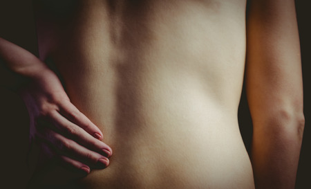 woman with a back injury on black backgroundの写真素材