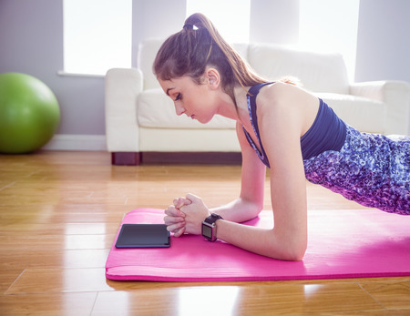 Fit woman doing plank on mat at home in the living room
