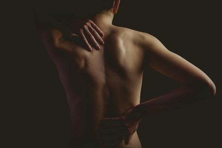 woman with a back injury on black backgroundの写真素材