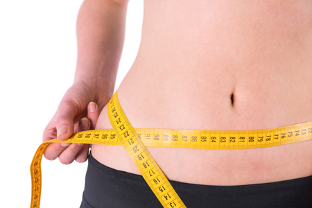 slim woman measuring waist with tape measure on white backgroundの写真素材