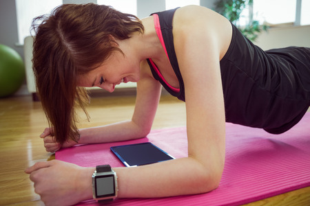 Fit woman doing plank on mat at home in the living room