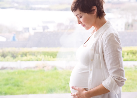 Pregnant woman holding her bump at home