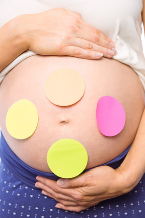 Pregnant woman with stickers on bump on white backgroundの写真素材
