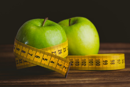 Green apples with measuring tape on wooden background