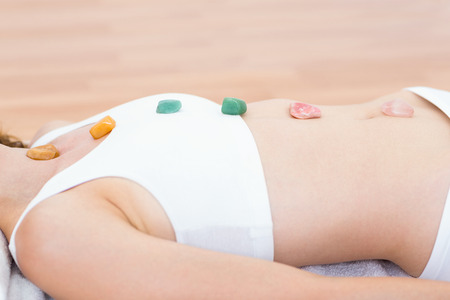 Relaxed brunette lying on mat with stones on wooden floorの写真素材