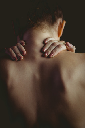 Nude woman with a neck injury on black backgroundの写真素材