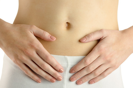 Slim woman touching her belly on white backgroundの写真素材