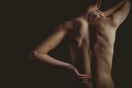 Nude woman with a neck injury on black backgroundの写真素材