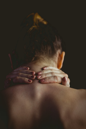 Nude woman with a neck injury on black backgroundの写真素材