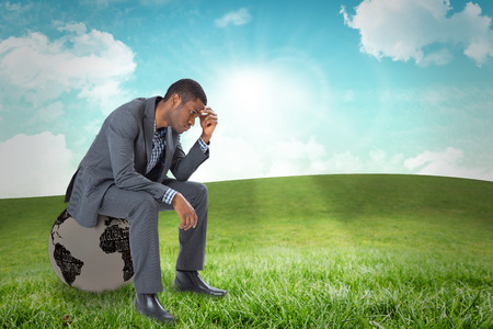 Thinking businessman sitting against field and skyの写真素材