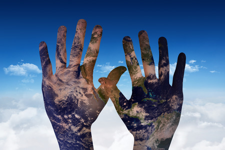 Hands against bright blue sky over cloudsの写真素材