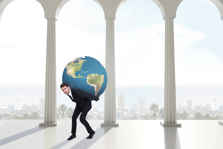 Businessman carrying the world against bright room with columnsの写真素材