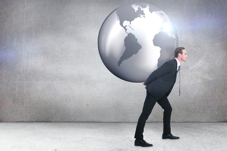Businessman carrying the world against grey roomの写真素材