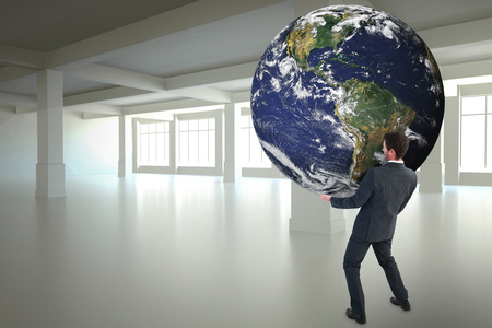 Businessman carrying the world against white room with windowsの写真素材