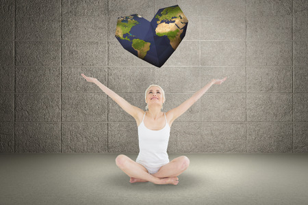 Toned young woman sitting with arms outstretched against grey roomの写真素材