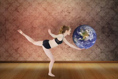 Side view of a sporty young woman standing on one leg against grimy roomの写真素材