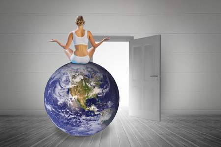 Fit woman doing yoga against open door on white wallの写真素材