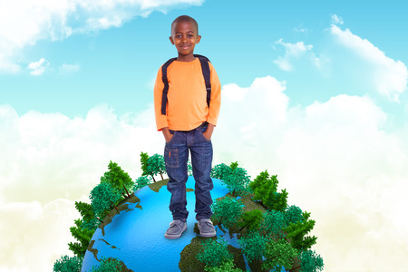 Cute elementary pupil smiling at camera against blue skyの写真素材