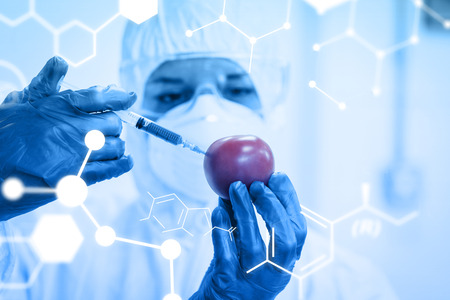 Science graphic against researcher in protective suit injecting tomato at labの写真素材