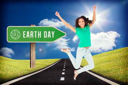 Pretty brunette jumping and smiling against road leading out to the horizonの写真素材