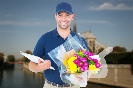 Happy flower delivery man holding clipboard against notre dam in parisの写真素材
