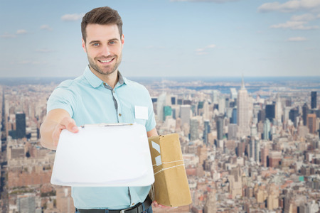 Delivery man with package giving clipboard for signature against new york