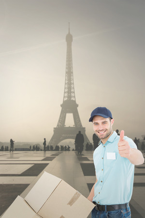 Delivery man with cardboard boxes gesturing thumbs up against eiffel towerの写真素材