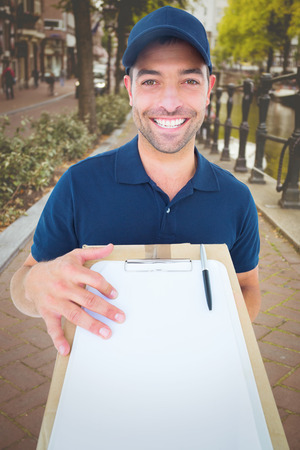 Happy delivery man with package and clipboard against bike path in amsterdamの写真素材