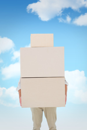 Courier man carrying cardboard boxes against blue skyの写真素材