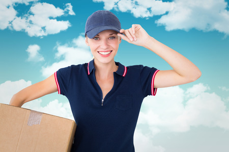 Happy delivery woman holding cardboard box  against blue skyの写真素材