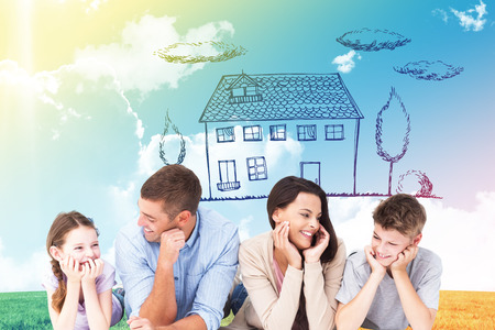 Family lying with head in hands against blue sky over green fieldの写真素材