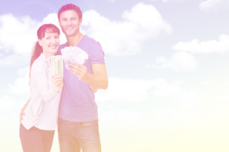 Couple holding fans of cash against blue skyの写真素材