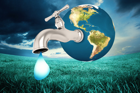 Earth with faucet against blue sky over green fieldの写真素材