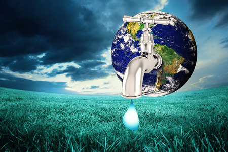 Earth with faucet against blue sky over green fieldの写真素材